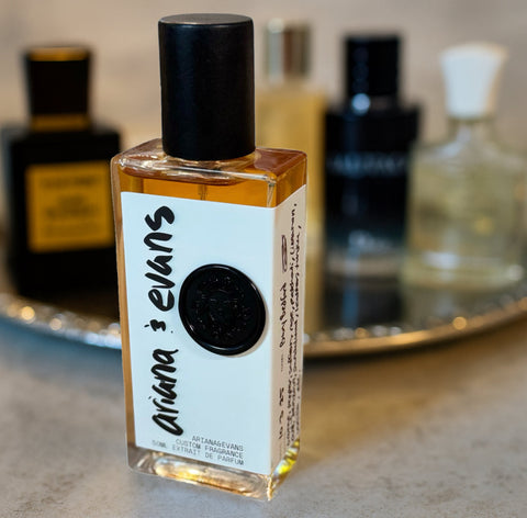 Luxury perfume bottles in dramatic lighting, symbolizing the hidden truth behind designer fragrances and Ariana & Evans’ artisanal approach.